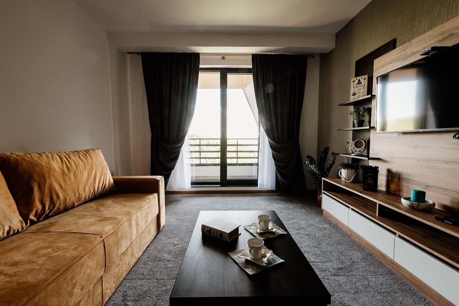 A cozy living room with a brown sofa, wooden coffee table and large windows