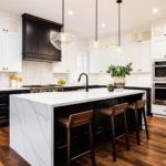 A trio of oversized glass pendant lights with brass fittings hanging over a large kitchen island, serving as a dramatic focal point in a modern, stylish kitchen.