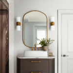 A modern bathroom with a white oval vessel sink on a white marble-top, natural wood fluted vanity, a round mirror, and dry grasses for decor.