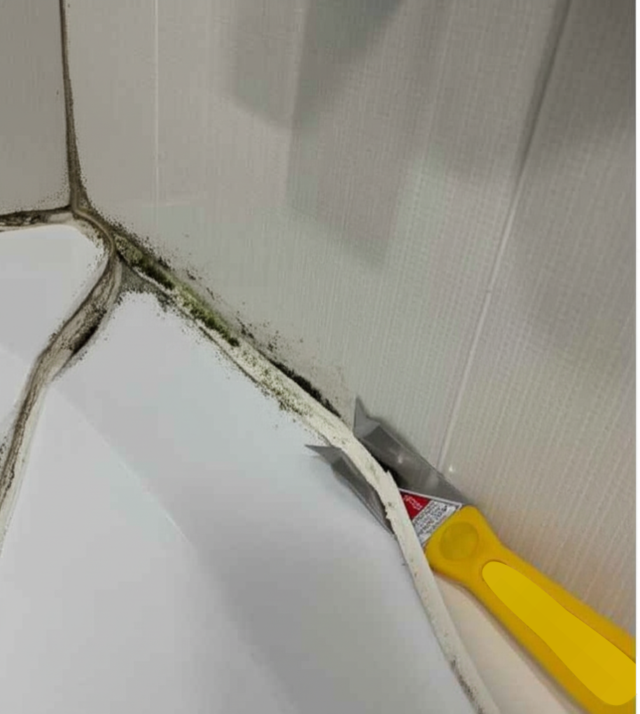 removing-old-moldy-silicone-sealant-process.jpg Close-up of hands using a knife and scraper to remove old, moldy silicone sealant from the edge of a bathtub or sink.